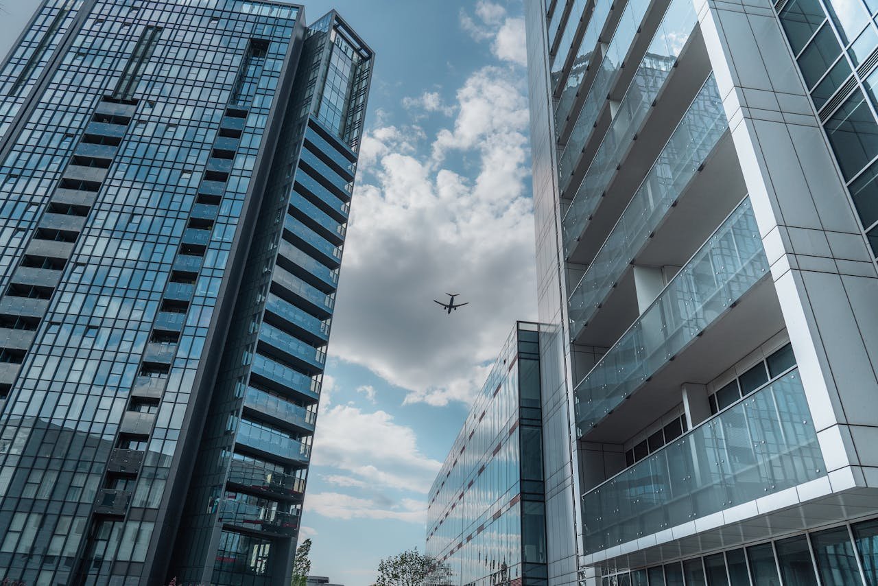 Modern skyscrapers in Poznań with an airplane soaring above on a clear day.